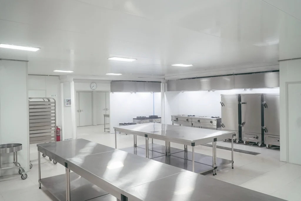 Dapur komersial modern dan higienis dengan meja stainless steel, oven, dan pendingin Solex, ideal untuk operasional program MBG berskala besar.